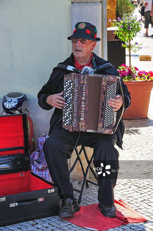 在葡萄牙阿尔加维地区洛莱圣弗朗西斯科广场街角拉手风琴的老人图片素材