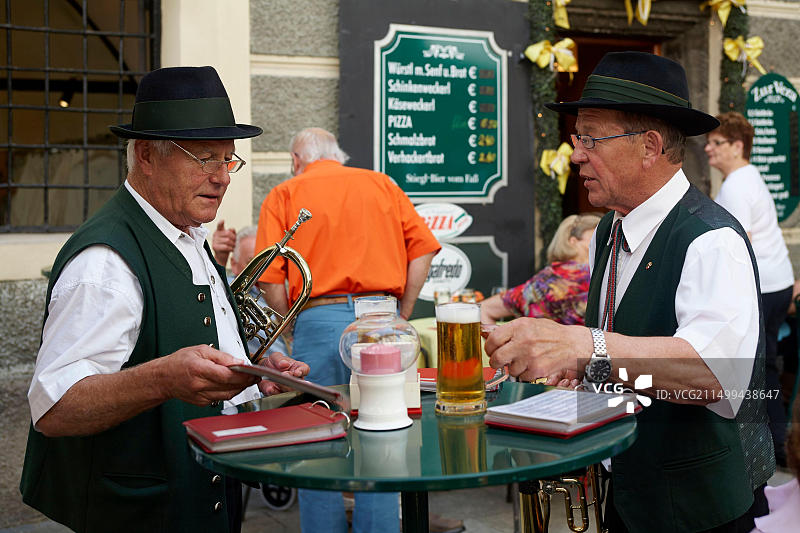 奥地利萨尔茨堡：身着传统服饰的号手在露台餐厅喝啤酒图片素材