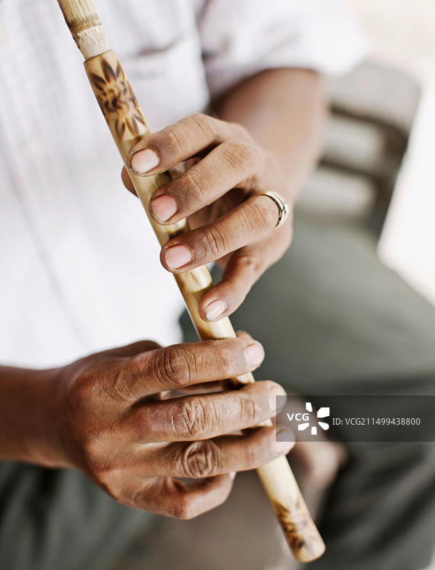 在柬埔寨金边郊外的家中，乐器制造商 Yim Seychot 演奏柬埔寨长笛图片素材