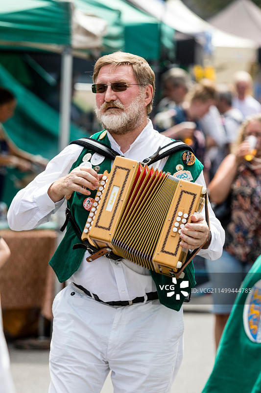 40多岁的白人男子，民间音乐家，来自莫尔登格林夹克莫里斯队的莫里斯舞者在年度三明治民间和啤酒节期间演奏手风琴图片素材