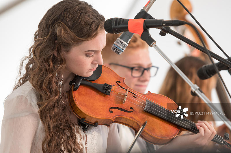 年轻女子在格林斯伯勒的音乐团体中专注地拉小提琴图片素材