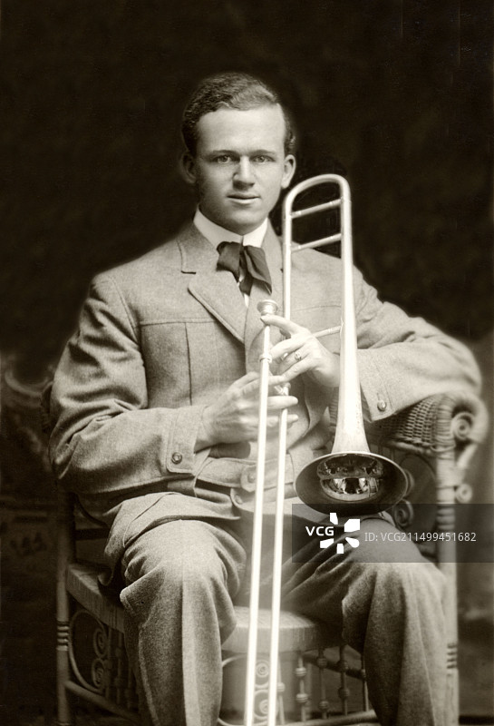 坐在藤椅上吹长号的音乐家图片素材