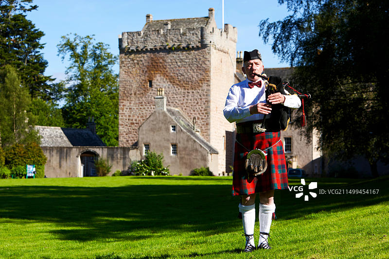 在苏格兰城堡前演奏苏格兰风笛的乐手图片素材