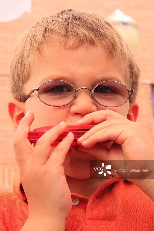 男孩在弗吉尼亚州加拉克斯的树叶与弦乐艺术节上吹口琴图片素材