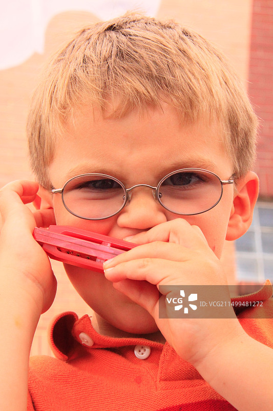 男孩在弗吉尼亚州加拉克斯的树叶与弦乐艺术节上吹口琴图片素材