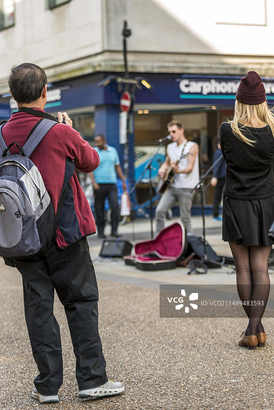 路人在牛津科恩市场街拍摄街头艺人青年音乐家图片素材