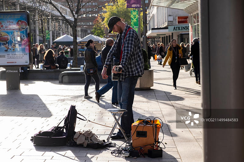 在谢菲尔德冬季步行购物区演奏原声吉他和放大器的街头艺人图片素材