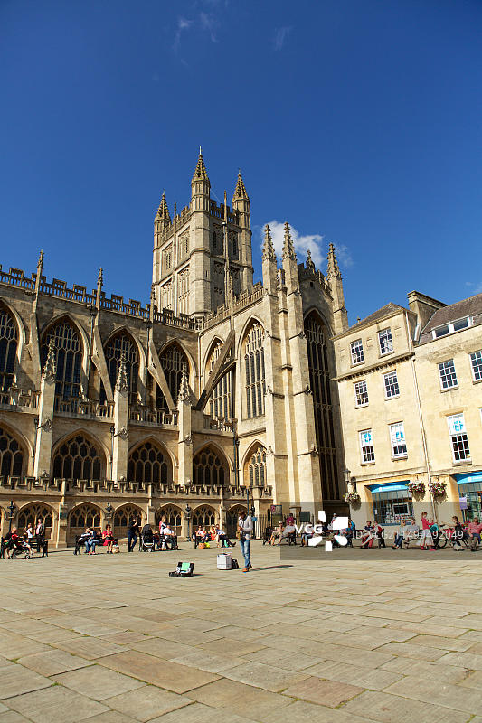 在广场上以巴斯修道院为背景演奏萨克斯管的街头艺人图片素材