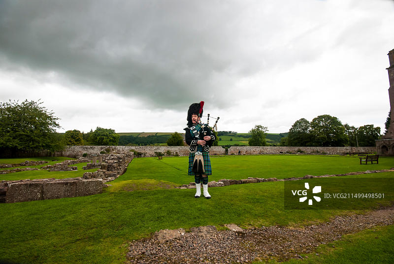 孤独的风笛手在苏格兰边境小镇梅尔罗斯的梅尔罗斯修道院遗址中演奏图片素材