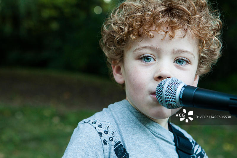唱着歌的卷发小男孩图片素材