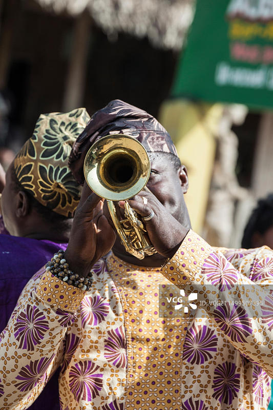 非洲贝宁冈维耶，身着传统服装的男子吹喇叭图片素材