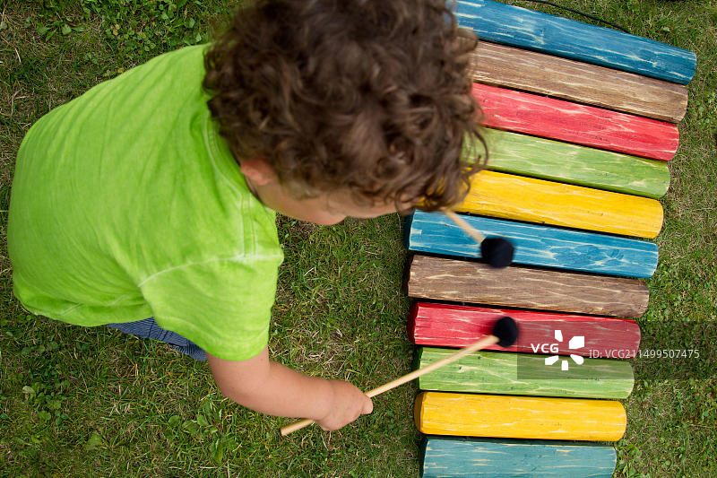 儿童学习音乐：男孩在花园里演奏木琴图片素材