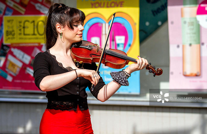 英国苏格兰泰赛德邓迪：一位年轻时尚的女小提琴手在Overgate购物中心外演奏古典音乐图片素材