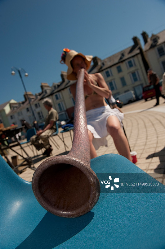 年轻女子在英国威尔士阿伯里斯特威斯海滨长廊上演奏迪吉里杜管图片素材