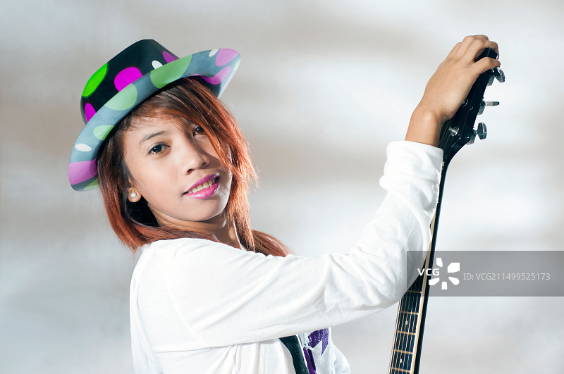 年轻亚洲女子在工作室里抱着吉他图片素材