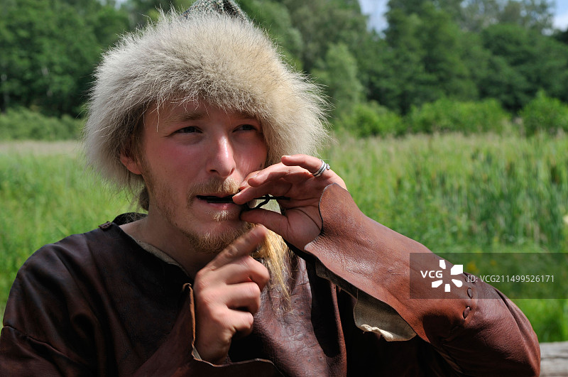 身穿维京服装的男人在瑞典比约克岛上的维京镇比尔卡演奏犹太竖琴，联合国世界遗产图片素材