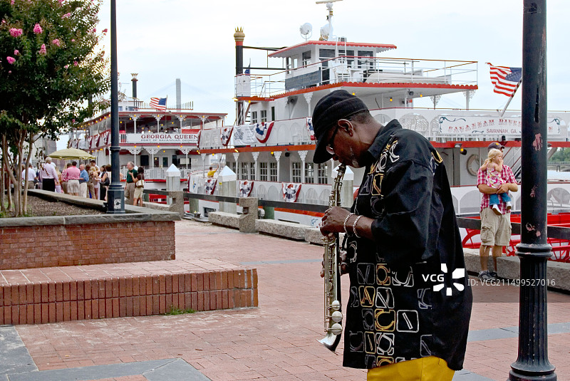 萨凡纳河上的街头音乐家和游船图片素材