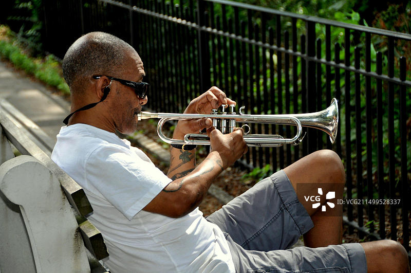 纽约：坐在河滨公园长椅上吹小号的男人图片素材