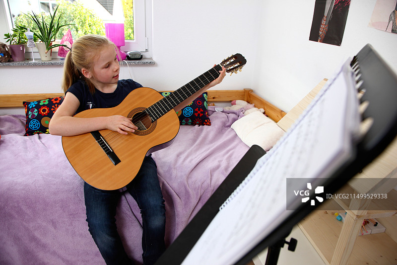 10岁女孩在家弹吉他，学习演奏乐器图片素材