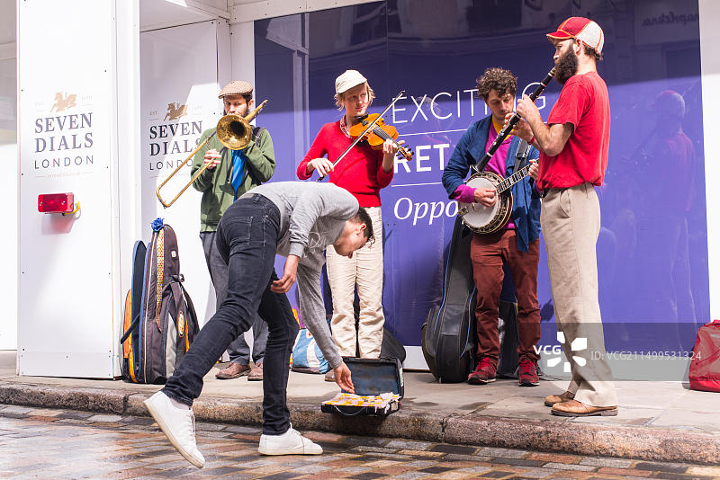 在英国伦敦七表盘街头艺术节期间，男子向四重奏铜管乐队的街头艺人提供帮助图片素材