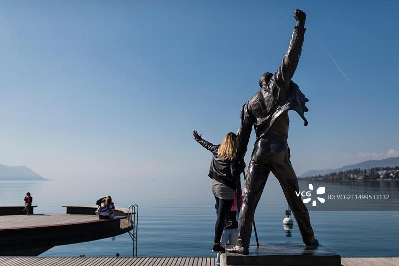 在蒙特勒日内瓦湖湖畔，游客与英国摇滚乐队皇后乐队已故歌手弗雷迪·默丘里的雕像合影图片素材