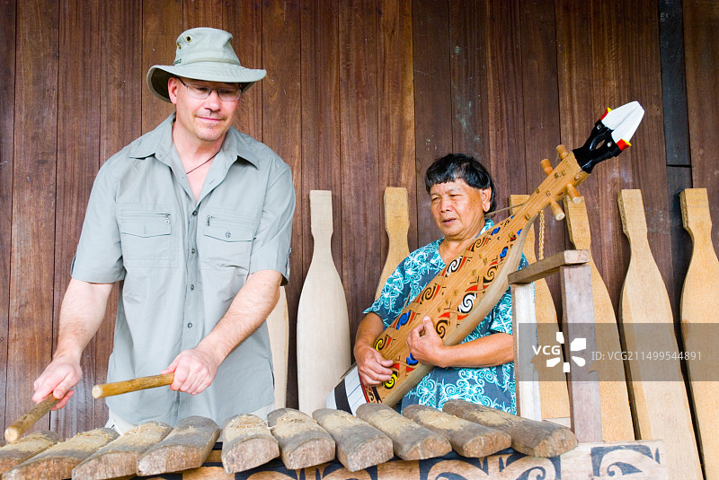 在马来西亚婆罗洲砂拉越文化中心，加拿大游客与伊班音乐家一起演奏音乐图片素材