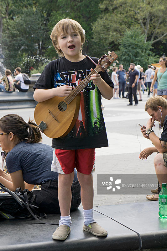 在家长监督下，9岁男孩在纽约市格林威治村华盛顿广场公园弹吉他赚小费图片素材