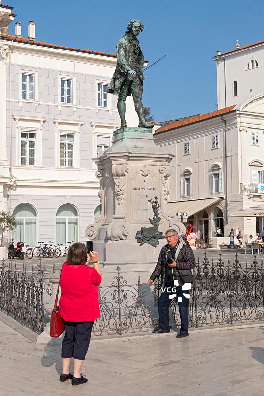 游客在斯洛文尼亚皮兰老城的塔尔蒂尼小提琴家雕像前合影图片素材