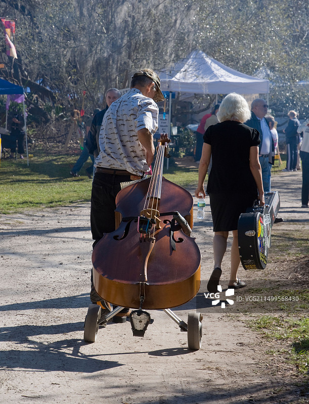 两名音乐家带着乐器前往佛罗里达州盖恩斯维尔花园节演出图片素材