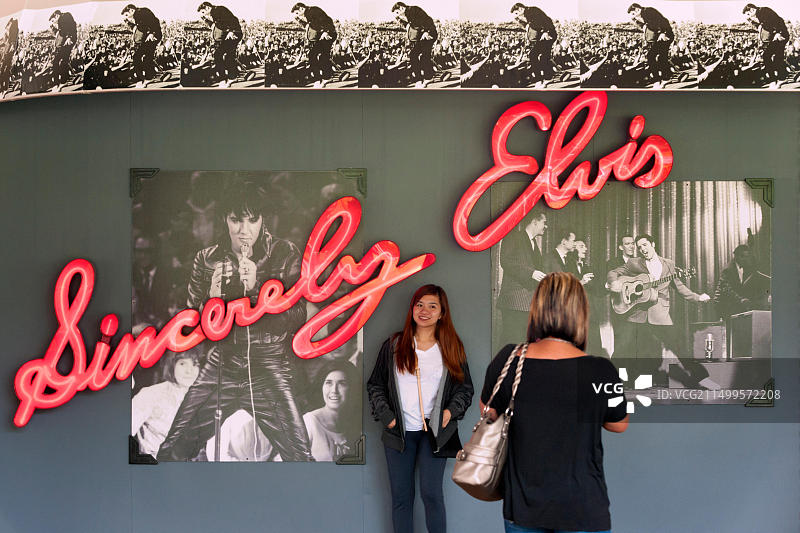 在美国田纳西州孟菲斯市的优雅园，在猫王霓虹灯标志前摆姿势的女人图片素材