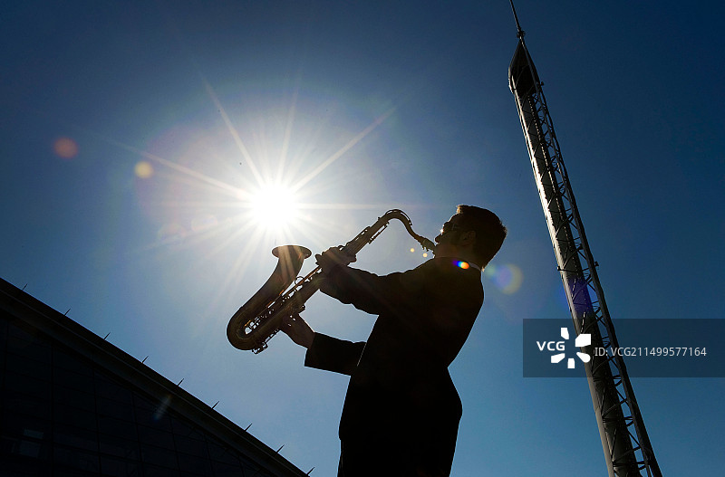 在格拉斯哥科学中心背景下吹萨克斯的男子轮廓图片素材