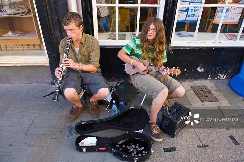 在英国什罗普郡勒德洛美食节期间，两个青少年在人行道上演奏单簧管和尤克里里琴图片素材