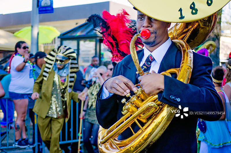 在阿拉巴马州莫比尔举行的乔·凯恩日狂欢节游行中，埃克塞尔西奥乐队成员演奏低音萨克斯管图片素材
