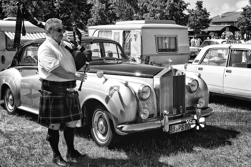 风笛手在劳斯莱斯银云汽车旁演奏苏格兰风笛图片素材