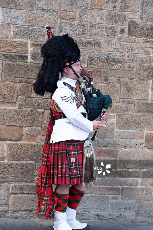 穿着苏格兰传统服装，在街上吹奏风笛的男人图片素材