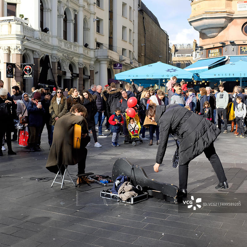 在英国伦敦莱斯特广场向街头艺人施舍的女人图片素材