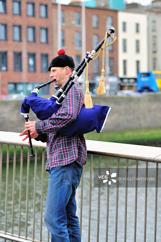 爱尔兰都柏林，利菲河上的半便士桥，风笛手正在演奏图片素材