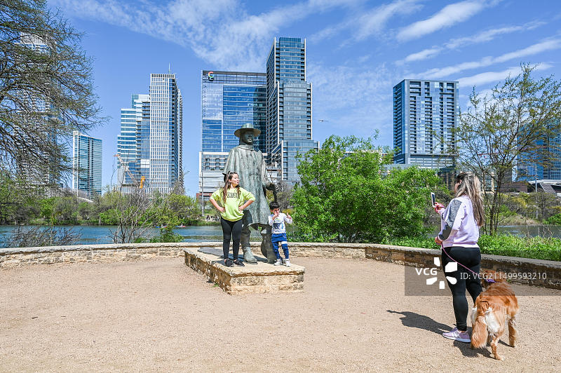 人们在德克萨斯州奥斯汀市都会区公园的史蒂夫·雷·沃恩雕塑前合影。他是一位出生于德克萨斯州达拉斯的蓝调吉他传奇人物。图片素材