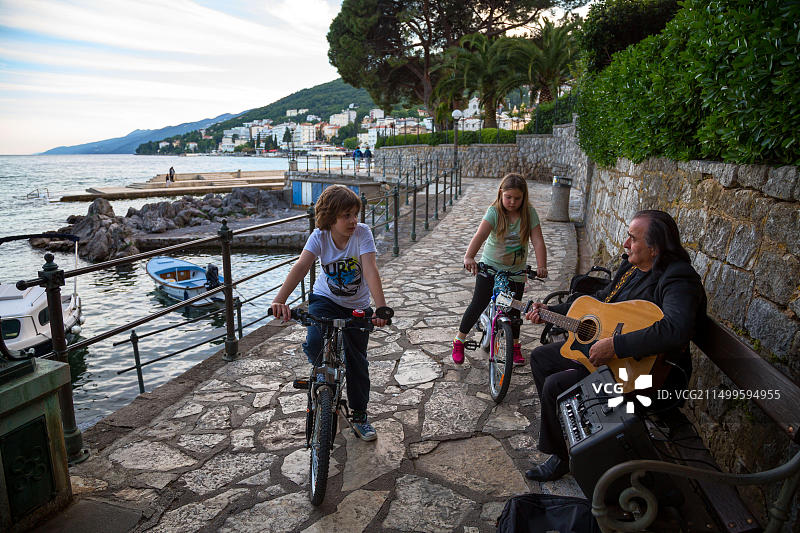 克罗地亚奥帕蒂亚：男人吉他唱歌谣，孩童聆听图片素材