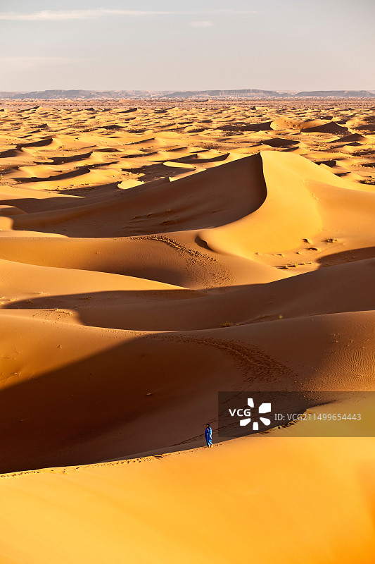 摩洛哥，米哈米德，埃尔格奇加沙丘。撒哈拉沙漠。当地柏柏尔人在沙丘上，背景是旅游营地，宿营地。图片素材