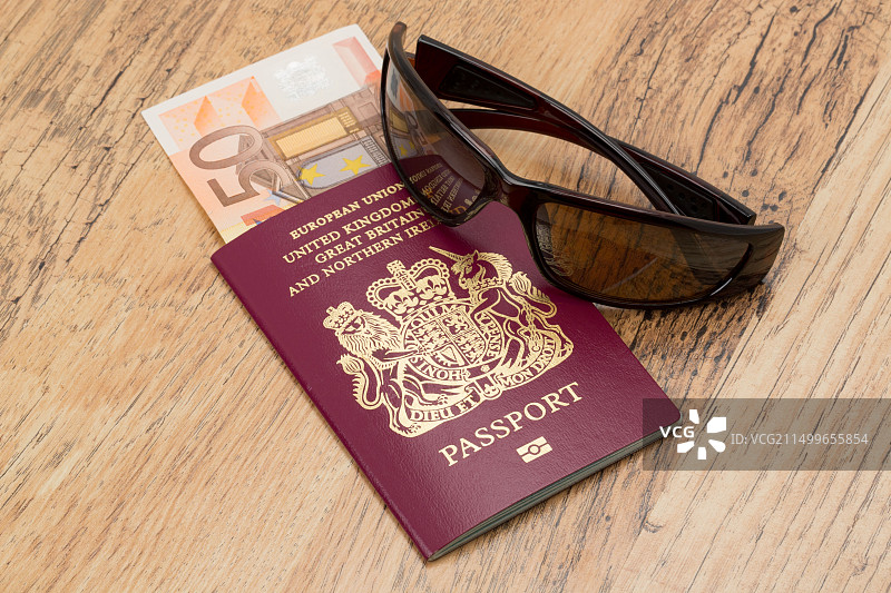 放在桌子上的英国护照、欧元和酷炫太阳镜 - 旅行主题图片素材