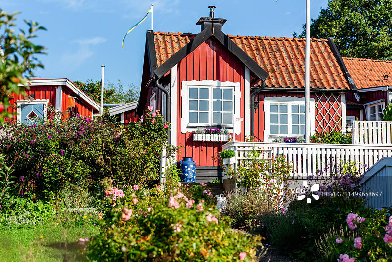 瑞典卡尔斯克鲁纳：城市周边旅游风光，红白相间的分配小屋和花园，蓝色牛奶桶图片素材