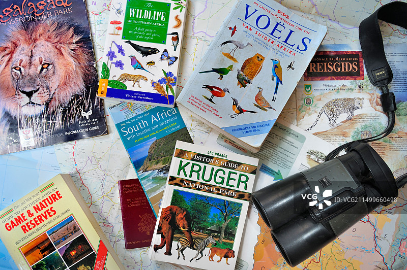 双筒望远镜、旅行指南、非洲野生动物书籍和南非地图，用于规划狩猎假期图片素材
