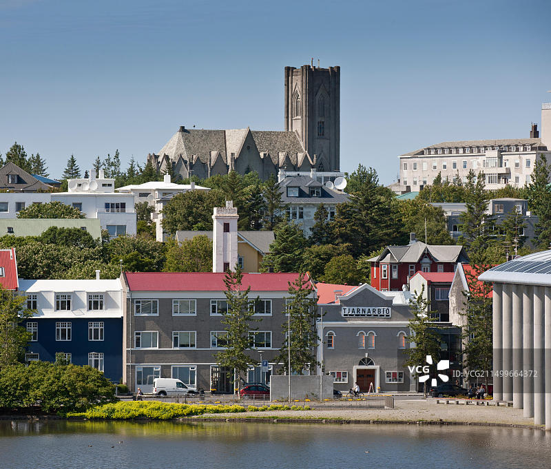 冰岛雷克雅未克，兰达哥特教堂背景下的池塘边的房屋图片素材