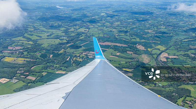 从伦敦盖特威克机场乘坐途易航空公司的空中巴士飞往意大利西西里岛。从飞机舷窗看到的英国乡村田野图片素材