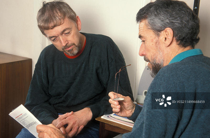 与医生咨询旅行医疗宣传单的中年男子图片素材