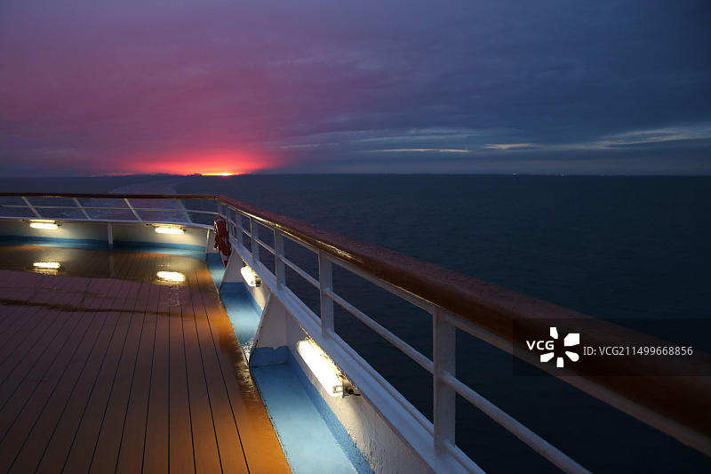 邮轮甲板上粉色云彩的日落美景：平静的海洋之旅图片素材