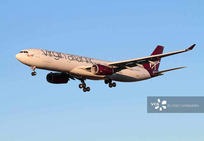 维珍航空空客A330-300型客机在日落时分的蔚蓝天空下进近降落，远程航空旅行图片素材