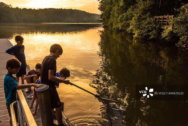 男孩们在佐治亚州温德尔的亚戈堡州立公园营地湖边码头钓鱼（美国）图片素材