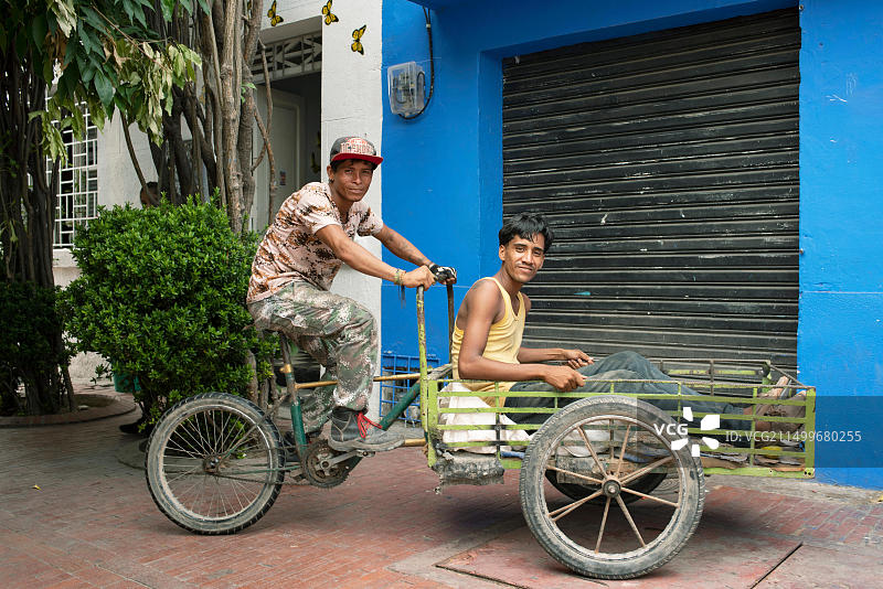 两位年轻拉丁裔男子在货运自行车上的工作后肖像，哥伦比亚圣玛尔塔，环保旅行肖像，编辑用途，2018年9月图片素材